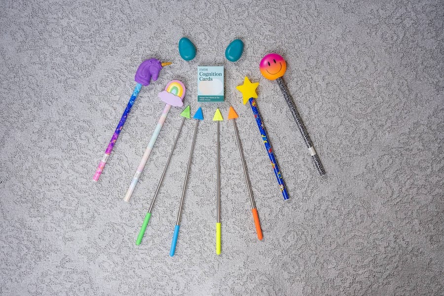 EMDR equipment laid out on a rug: several wands with coloured tips, two handheld tactile pulsers, and a deck of EMDR cognition cards