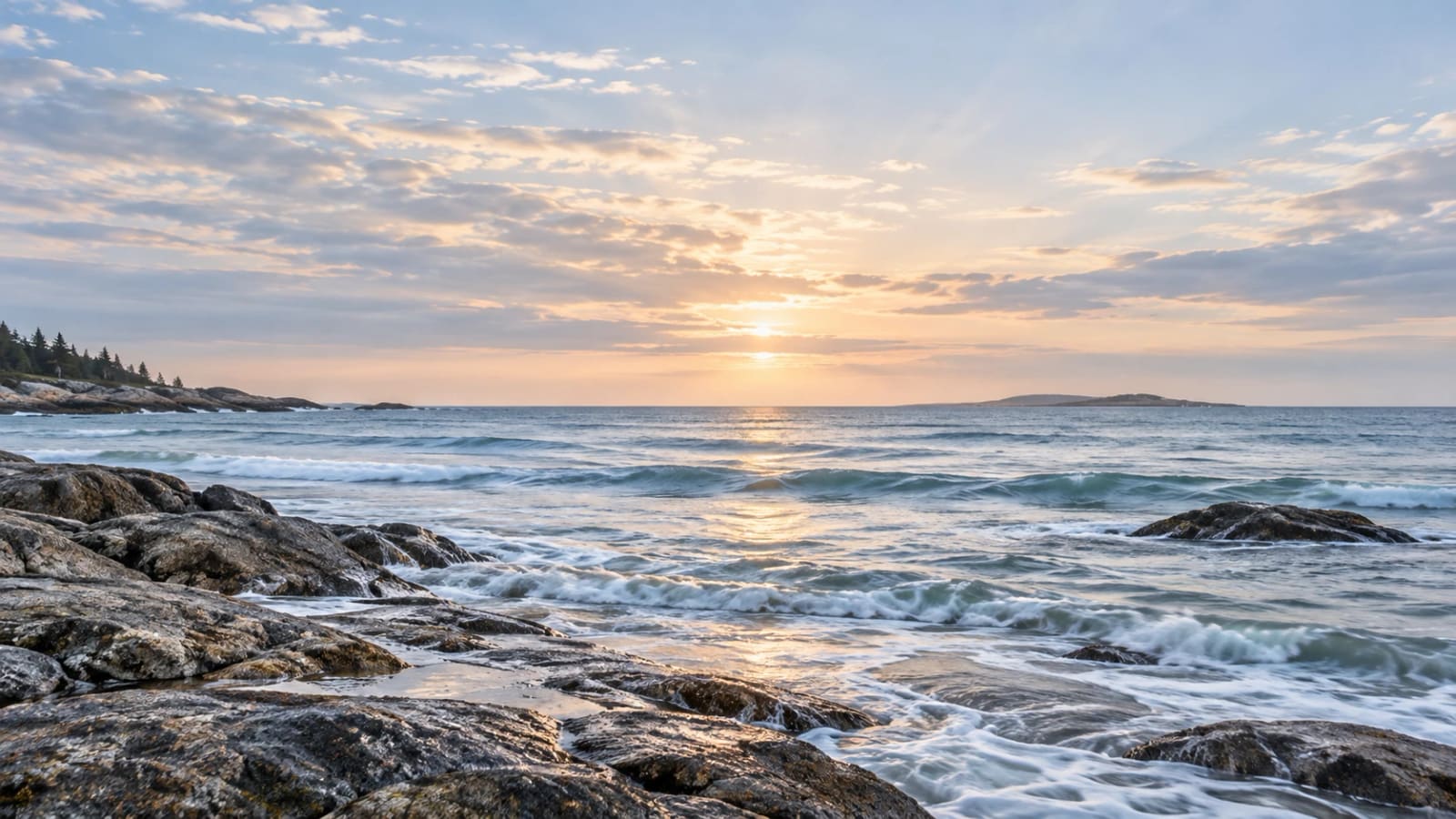 Sunrise over an open sea horizon, seen across wet rock at the shoreline
